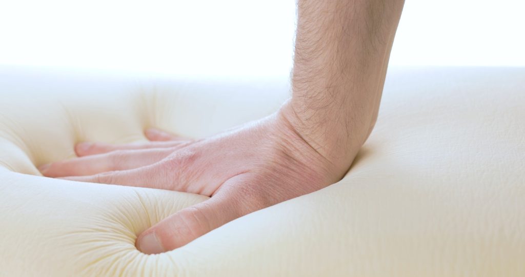 Hand is pressing a memory foam mattress.